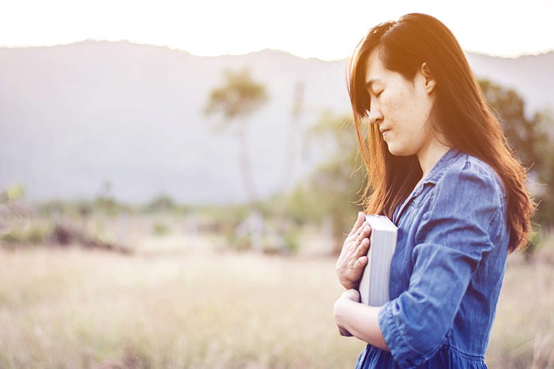 Woman holding bible praying